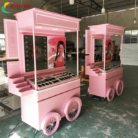 Chariot de présentation mobile haut de gamme rose personnalisé pour cosmétiques et parfums, avec auvent et roues, idéal pour les événements en centre commercial