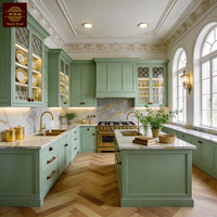 Meubles de cuisine personnalisables vert sauge, style classique français, en bois massif, avec grand îlot central et armoire de rangement en bois.
