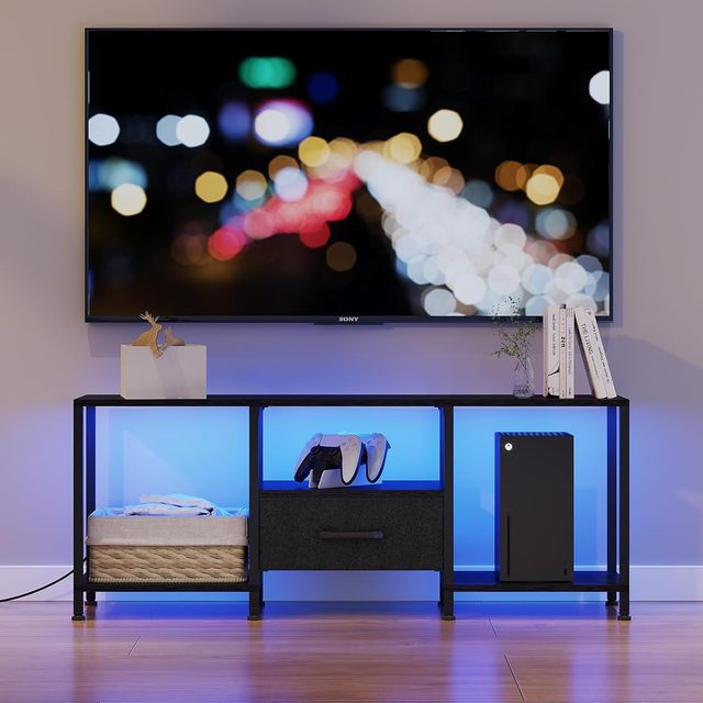 The TV cabinet is equipped with LED lights, an entertainment center, and also has open shelves and fabric drawers.