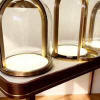 Vitrine de luxe en verre en forme de dôme avec éclairage LED et base métallique pour présentation de bijoux haut de gamme en boutique ou en showroom