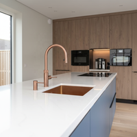 Ensemble d'armoires de cuisine sur mesure en finition bleu foncé avec évier en cuivre, plaque de cuisson à induction et four encastré