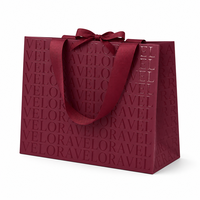 Sac en papier de luxe bordeaux à motif gaufré avec poignée en ruban gros-grain et nœud décoratif pour boutique de vêtements