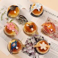 Une pâtisserie au jaune d'œuf transparente en forme de blister rond en plastique, avec un macaron doré et une pâtisserie à la crème pâtissière