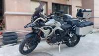 Moto de tourisme d'aventure à deux cylindres refroidie par eau de 502 cm3, blanche et noire, avec bagages et barres de protection entièrement en aluminium