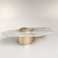 Table basse en marbre courbé avec détails dorés abstraits, style moderne et luxueux, pour salon ou comme table d'appoint.