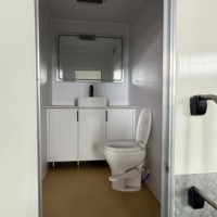 Remorque WC portable moderne et personnalisable de 4 m en panneaux sandwich pour extérieur, écologique, avec raccordement à l'eau.