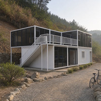 Maison préfabriquée à deux étages avec façade vitrée ouverte et terrasse de jardin