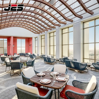 Ensemble de mobilier de patio J2S en métal et bois avec coussin et table, idéal pour les restaurants commerciaux modernes en extérieur et les stations balnéaires.