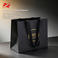 Sac en papier noir mat OEM avec poignée en ruban gros-grain et badge circulaire en feuille d'aluminium pour la vente au détail en boutique