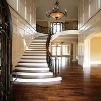 Escalier courbé classique avec des motifs en fer forgé sur mesure, marches en bois et en marbre