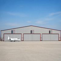 Hangar d'avion multi-baies à bordures rouges avec trois portes coulissantes, entrée latérale, espace d'accueil pavé et accès à l'aérodrome