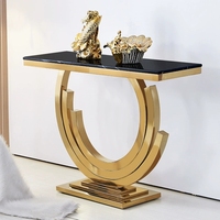 Table console de luxe moderne pour salon, en forme de demi-lune, longue et mince, avec plateau en marbre noir et base carrée en métal doré.