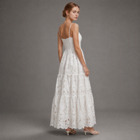 Robe longue blanche en pur coton avec dentelle florale brodée, bretelles spaghetti, taille haute et volants étagés, idéale pour les vacances