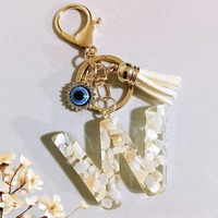 Porte-clés Alphabet en résine effet grain de coquille crème, avec pendentif œil porte-bonheur en strass et pompon en daim blanc cassé, cadeau personnalisé