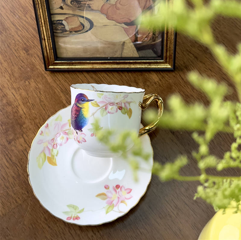 A cup and a plate of flowers and birds