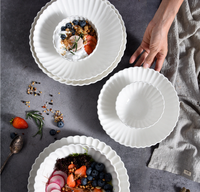 Servies van wit porseleinen kommen en borden met gegolfde rand, milieuvriendelijk, BPA-vrij, voedselveilig, met aangepast logo, modern design, geschikt voor salade en soep.