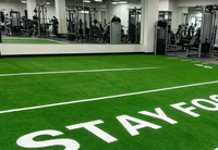 Césped artificial negro para gimnasio con línea de salida y marcas de carriles, tapete deportivo antideslizante con absorción de impactos para centros de fitness.
