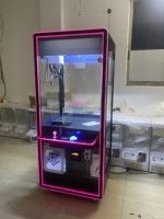 Machine à griffes à monnayeur avec cadre LED néon, vitrine en verre, commande par joystick et fente pour les prix, pour utilisation en boutique de cadeaux dans un centre commercial