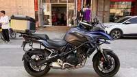 Moto de tourisme d'aventure à deux cylindres refroidie par eau de 502 cm3, blanche et noire, avec bagages et barres de protection entièrement en aluminium