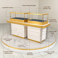 Comptoir de présentation de bijoux compact et combiné, vitrine en verre à cadre fin doré avec base de rangement à tiroirs blancs et plateforme ronde en marbre
