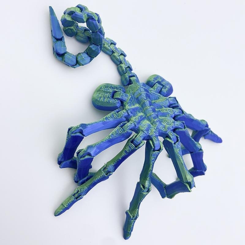 Insecto azul y verde de 24 cm que se acurruca en la cara.