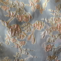 Tissu jacquard brodé en organza transparent métallisé, motif floral embossé dégradé noir, léger (69 g/m²), pour robe de soirée.