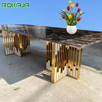 Table à manger de villa haut de gamme, design luxueux, pieds en acier inoxydable doré incrustés de pierres, plateau rectangulaire en marbre.