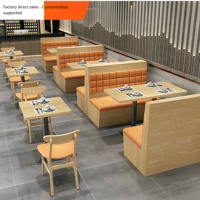 Ensemble de banquettes en bois clair avec chaises rembourrées orange beige et tables à piétement noir pour restaurant moderne
