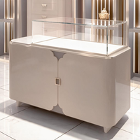 Vitrine de luxe pour bijoux avec plateau en verre, finition crème brillante, porte festonnée, poignée dorée, verre trempé, comptoir de boutique de détail