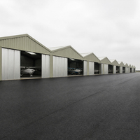 Hangar d'avion intérieur avec structure à voûte haute, porte à ouverture rapide, aile de service et accès à l'aérodrome