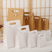 Sac cadeau de luxe écologique monochrome à thème nœud, avec poignées découpées, en carton ivoire, estampage à chaud et boucle adhésive pour cadeaux de fête
