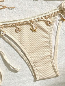 Bikini de mujer con parte inferior de tanga acanalada, ribete de encaje y dijes de concha, color beige. - Product Image 2