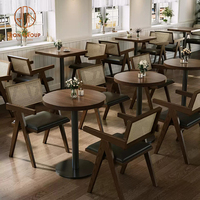 Ensemble de mobilier pour café-restaurant : tables carrées en bois avec base métallique, chaises en rotin à dossier en bois et banquette.