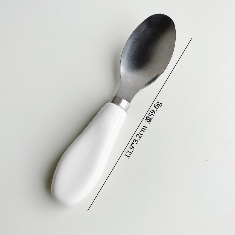 Cuchara para queso con mango de cerámica blanca.