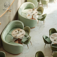 Ensemble de meubles pour café, restaurant, salon de thé : fauteuils en cuir vert avec pieds en bois, tables rectangulaires en bois et canapé banquette vert.