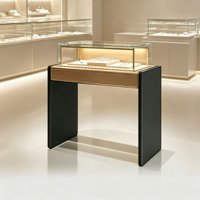 Vitrine à bijoux moderne et élégante avec dessus en bois clair, panneau latéral foncé, armoire en verre transparent avec éclairage LED chaud intégré pour la vente au détail de bijoux