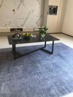 Table basse rectangulaire grise de luxe avec cadre en V asymétrique, pieds en métal noir, coins arrondis, sur mesure pour salon