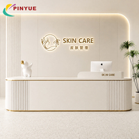 Comptoir d'accueil contemporain blanc à niveaux avec éclairage LED et finition dorée pour clinique de beauté, spa et salle d'exposition