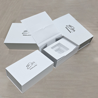 Boîte en carton rigide blanche de luxe avec logo argenté en forme de livre Coffrets cadeaux magnétiques pliants Insert en mousse EVA Stratification mate de crème pour le visage