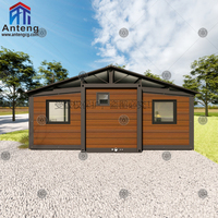 Maison conteneur pliable extensible en bois foncé avec toit à pignon et terrasse, spacieuse et privée, pour famille ou invités