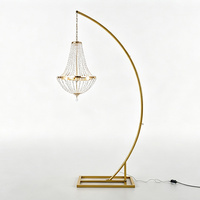 Lustre suspendu moderne et élégant en cristal, support doré incurvé pour mariage, idéal pour réceptions intérieures et allées.