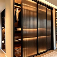 Dressing sur mesure Senger en mélamine bois clair avec îlot central et étagères éclairées par LED – Armoire de luxe moderne pour chambre à coucher