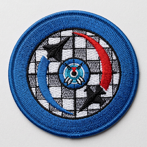 Parche bordado circular con borde azul y diseño de objetivo con flechas rojas y azules sobre fondo a cuadros - Product Image 1