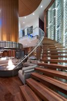 Escalier préfabriqué courbé en acier et bois, durable, avec garde-corps en verre intérieur et marches antidérapantes