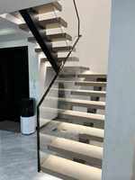Escalier sur mesure à structure à poutre unique avec marches en pierre et garde-corps en verre invisible