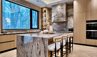 Meuble de cuisine moderne de luxe en bois clair sur mesure avec porte à panneau plat, îlot cascade en marbre et crédence pour villa