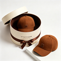 Boîte cadeau rigide ronde noire personnalisée avec ruban doré et doublure en velours pour casquette de baseball