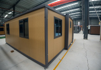 Conteneur modulaire extensible de 20 pieds avec structure grise et finition bois clair, moderne, étanche et résistant au vent, pour maison d'hôtes de jardin ou chantier