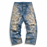 Jean en denim bleu avec empiècements patchwork clairs sur le devant, détails de poches effet éclaboussures multicolores et ourlets bruts usés