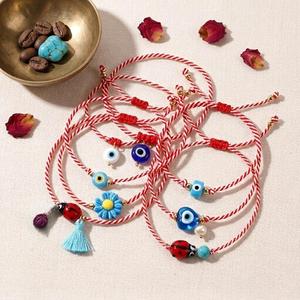 Pulsera de cuerda trenzada roja y blanca hecha a mano Resoul con amuleto de mariquita y flor margarita, joyería de protección y buena suerte para mujer - Product Image 1